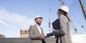 smiling-engineers-shaking-hands-at-construction-site-for-architectural-project